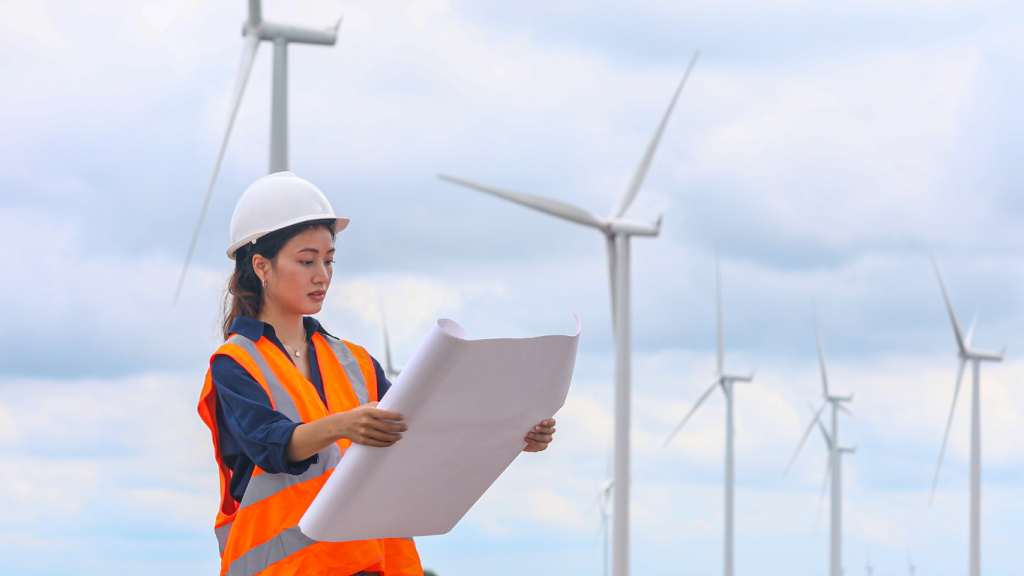 Woman standing in front of wind turbines holding construction plan